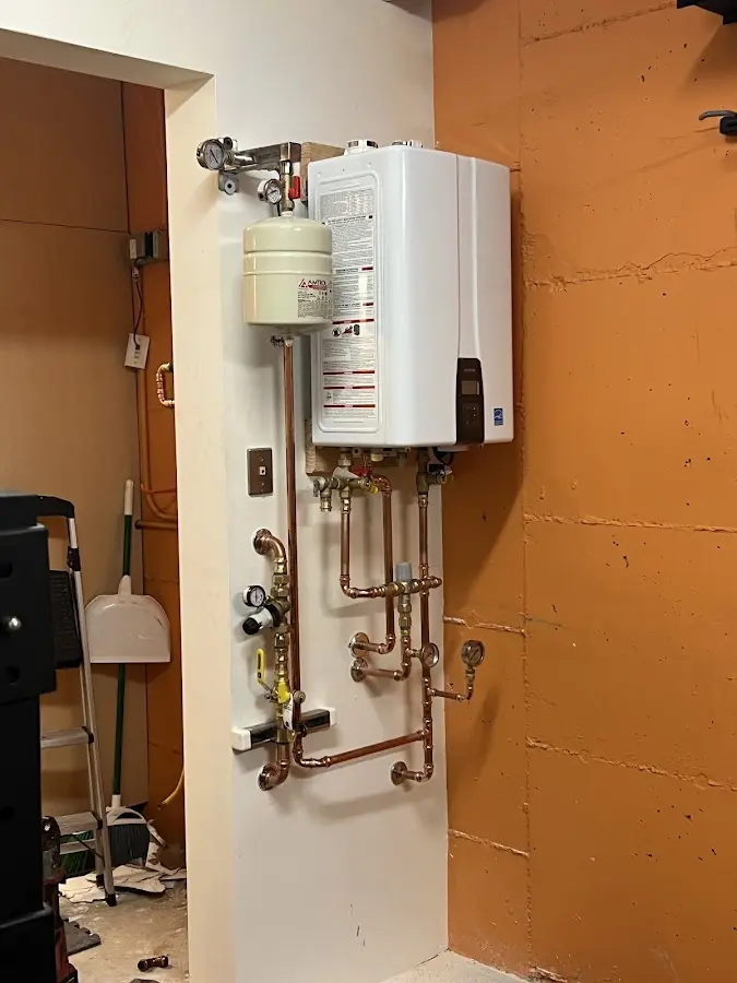 Plumbing technician inspecting water heater connections in Grantham